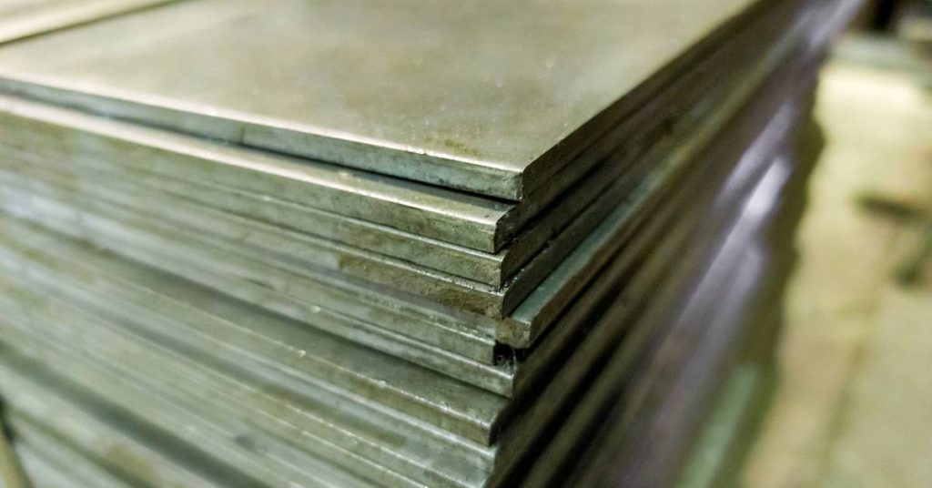 Stacks of cold-rolled steel sheets, which could be made from ASTM A36 or A572 steel, in a warehouse or factory setting.